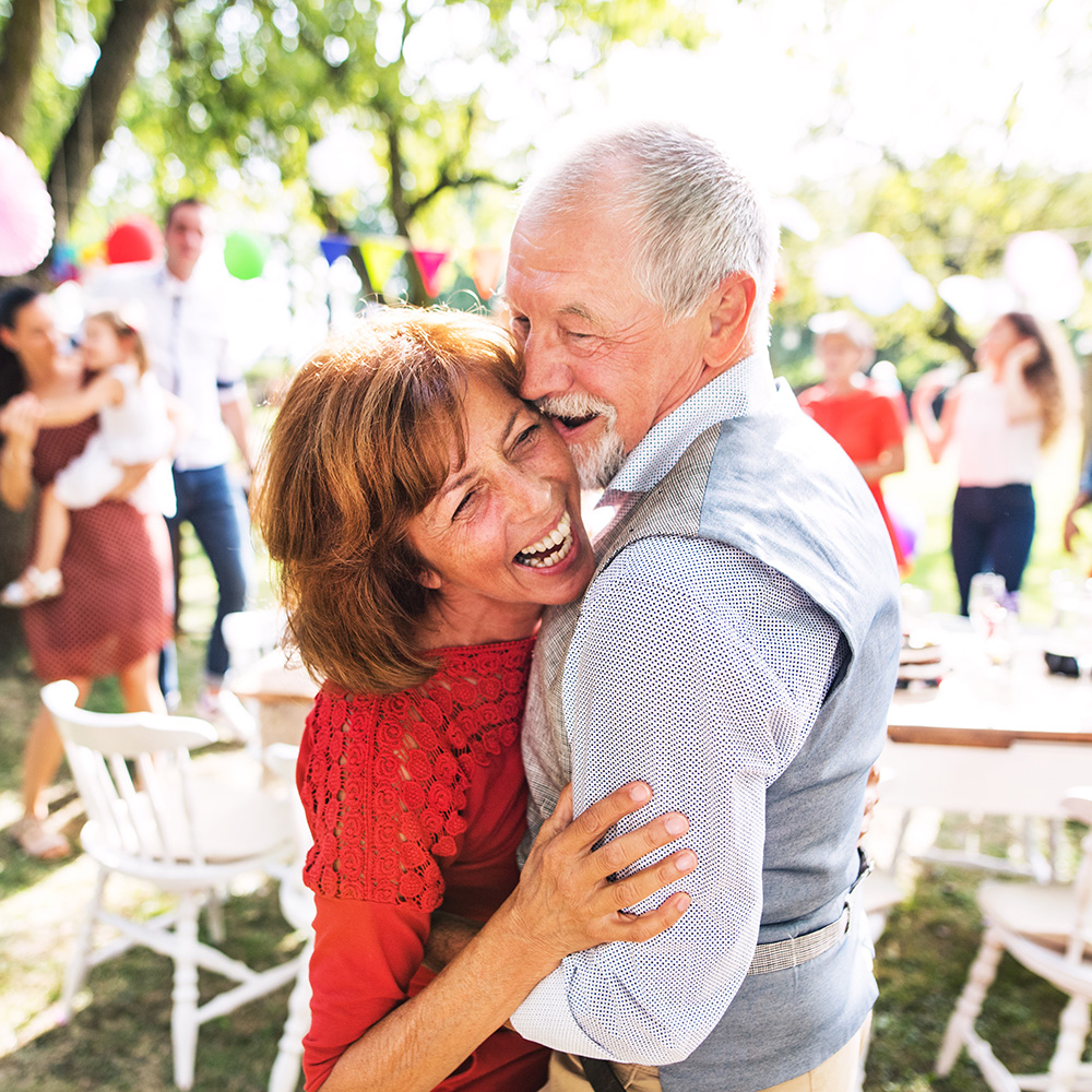 A senior couple dancing on a garden party or family celebration outside in the backyard